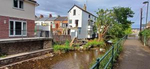 a house with a river in front of it at Brookside Lodge, central Dawlish in Dawlish