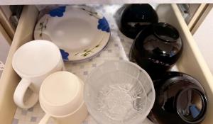 a drawer filled with cups and plates and a bottle at apartment hotel myu didymi in Utsunomiya