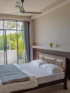 a bedroom with a bed and a large window at Surf's Up LOFT in Weligama