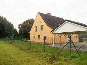 a yellow house with a fence in front of it at Ferienhaus "Am Wald" in Behrenwalde