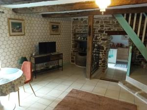 a living room with a tv and a stone wall at The Old Cider Press in Carnoët