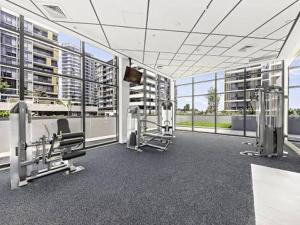 a gym with cardio equipment in a building with windows at Olympic Optimum Accor in Sydney