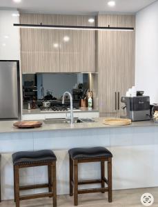 a kitchen with a sink and two bar stools at Olympic Optimum Accor in Sydney