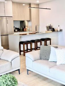 a living room with two white couches and a kitchen at Olympic Optimum Accor in Sydney +8 photos
