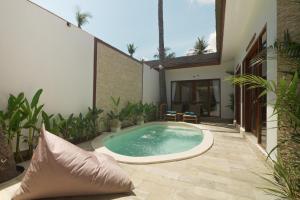 a swimming pool in the middle of a patio with plants at Gili Nomade Villas in Gili Trawangan