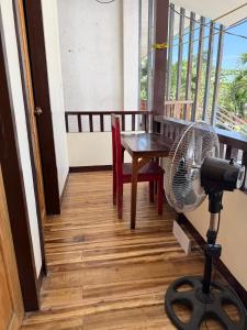 a fan on a stand on a balcony with a table at Pads Guesthouse in San Vicente