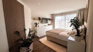 a bedroom with a bed and a window with plants at Modern Luxury Apartment in Karsau