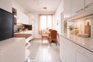 a kitchen with white cabinets and a dining table at Kristillan kartano in Tampere