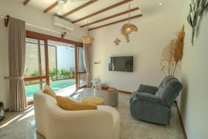 a living room with two chairs and a pool at Gili Nomade Villas in Gili Trawangan