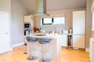 a kitchen with a island with two blue bar stools at Snowdrop Lodge in Errol +10 photos