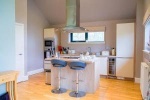 a kitchen with two stools at a kitchen island at Snowdrop Lodge in Errol