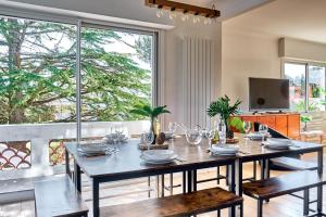 a dining room with a table and a large window at Villa Le Deck - Grande maison familliale proche plage in Arcachon