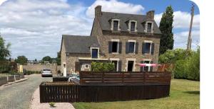 a brick house with a fence in front of it at Caravane revisité in Pleslin-Trigavou