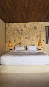 a bedroom with a bed with a stone wall at Villa Saraswati I in Uluwatu +47 photos