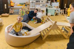 a young boy sitting in a wooden boat in a play room at OREA Spa Hotel Palace Zvon Mariánské Lázně in Mariánské Lázně