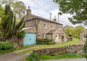an old stone house with a blue garage at Swale View in Feetham