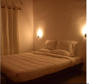 a bed with white sheets and pillows in a room at GP Estate Bungalow in Suryanelli