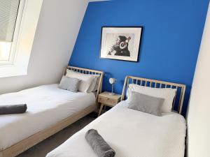 two beds in a room with a blue wall at Dawson House in Southampton