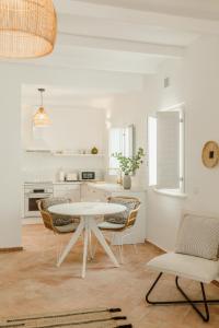 a white kitchen with a white table and chairs at Casa do Sol - Casas do Levante in Olhão