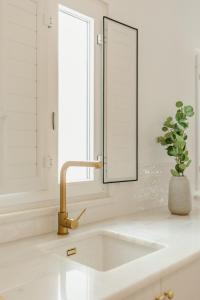 a sink in a bathroom with a mirror and a plant at Casa do Sol - Casas do Levante in Olhão +29 photos