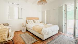 a white bedroom with a bed and a window at Casa do Sol - Casas do Levante in Olhão