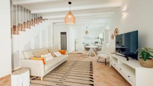 a living room with a couch and a tv at Casa do Sol - Casas do Levante in Olhão