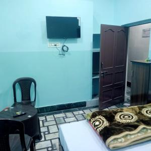 a room with a bed and a chair and a tv at Hotel THAR in Bikaner