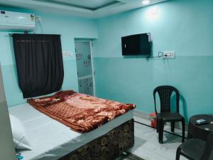a bed in a room with a tv and a chair at Hotel THAR in Bikaner