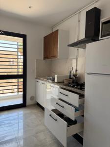 a kitchen with white cabinets and a white refrigerator at Le gris Perle in Sfax