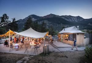 a group of people sitting at tables under tents at Huttopia La Clarée in Val-des-Prés