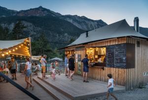 a group of people standing outside of a restaurant at Huttopia La Clarée in Val-des-Prés
