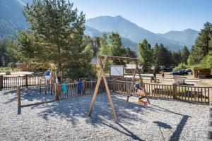 a child playing on a swing set in a playground at Huttopia La Clarée in Val-des-Prés +13 photos