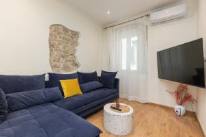 a living room with a blue couch and a flat screen tv at Aila Stay in Corfu