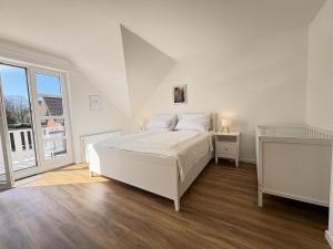 a white bedroom with a bed and a window at Allee 1G - Meerzeit in Dahme