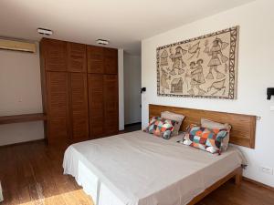 a bedroom with a bed and a painting on the wall at Maison des Alizés in Oussouye