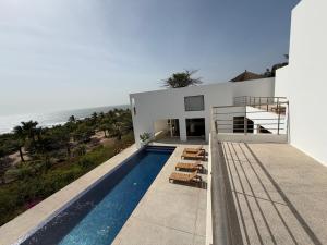 a house with a swimming pool next to the ocean at Maison des Alizés in Oussouye +25 photos