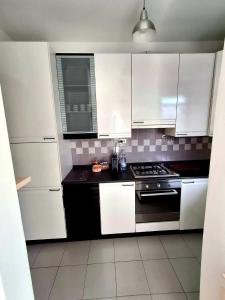 a kitchen with white cabinets and a stove at Sassonia beach in Fano +3 photos