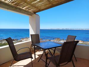 a table and chairs on a balcony with the ocean at Whale Watch Cottage in St. Helena Bay