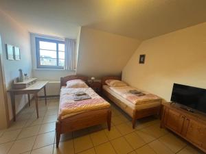ein kleines Zimmer mit zwei Betten und einem Fernseher in der Unterkunft Hotel Katharinenhöfchen in Salzwedel