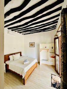 a bedroom with a bed with a black and white striped ceiling at Apartments Maliki, Matemwe in Matemwe