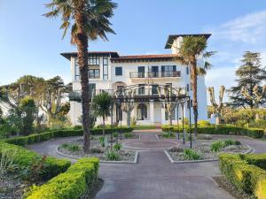 a large white building with palm trees in front of it at Residence de bordaberry in Urrugne