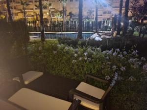 a park with two chairs and a bench and flowers at Superbe appartement à bouznika avec vue sur piscine et jardin privatif in Bouznika