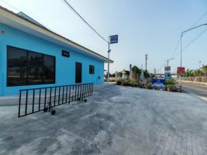 an empty parking lot next to a blue building at K-Am คราม อมตะ รีสอร์ต in Ban Yan Su