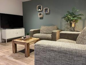 a living room with two chairs and a flat screen tv at Gastenverblijf Bladel in Bladel