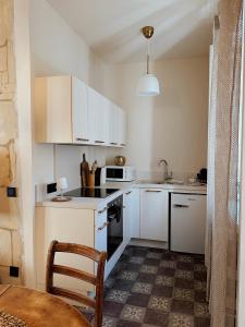a small kitchen with white cabinets and a table at Le Voisin des Arènes in Arles