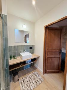 a bathroom with a sink and a wooden door at Le Voisin des Arènes in Arles