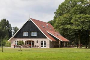 a large house with a black roof on a field at De Sterre in Losser