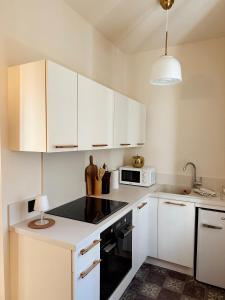 a kitchen with white cabinets and a black stove top oven at Le Voisin des Arènes in Arles +21 photos