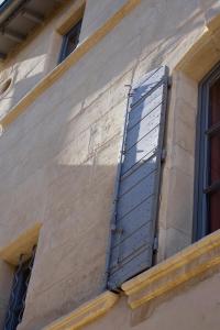 a blue shutter on the side of a building at Le Voisin des Arènes in Arles