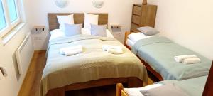 a room with three beds with towels on them at Báránykő Apartman in Pásztó